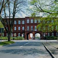 The photograph shows a road leading to a building with two large archways