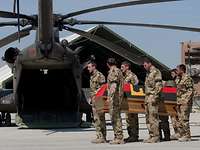 Soldaten tragen einen Sarg zu einem Hubschrauber