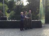 Urkunde von der Ministerin Nicole Nordholz hält Urkunde und den Pokal in Form einer Kugelhantel in Händen, neben ihr steht Ursula von der Leyen.