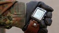 Eine Stoppuhr in einer Hand mit Handschuh