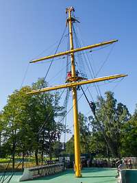 Lehrgangsteilnehmenden stehen draußen vor dem Gorch-Fock-Übungsmast. Offiziersanwärter stehen am Mast oder klettern hinauf