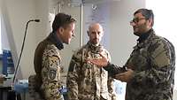 Zwei deutsche Soldaten stehen mit einem afghanischen Soldaten in einem Behandlungszimmer und unterhalten sich