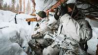 Zwei Soldaten hocken in einer überdachten Stellung aus Schnee. Einer beobachtet mit einem Fernglas die Umgebung.