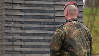 Soldat im Wald der Erinnerung an der Stele für die Gefallenen des Karfreitagsgefechts 2010