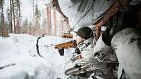 Soldaten hocken in einem Unterstand. Vor ihnen türmt sich Schnee auf.