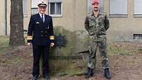 Admiral Rühle links und der Kommandeur des Feldjägerregiments stehen vor einem Stein für ein gemeinsames Foto.