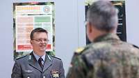 Zwei Soldaten stehen sich gegenüber, im Hintergrund ist ein Plakat mit der Aufschrift Coronavirus.