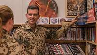 Ein deutscher Soldat zeigt einer Kameradin das Brettspielangebot des Betreuungsbüros