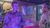 Ein deutscher Soldat überreicht einem Kameraden ein Getränk an der Bar