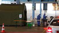 Autoschlange vor dem Testzelt innerhalb einer Messehalle.
