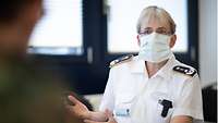 Frau Dr. Thinnes in einem weißen Arzthemd. Sie trägt eine Mund- und Nasenschutzmaske.