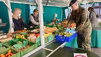 Oberstabsgefreiter Alexander Bartels füllt den Einkaufskorb mit den frischer Ware vom Markt.
