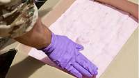 Ein Soldat mit Handschuhen platziert den Sprengstoff sorgfältig auf der unsicheren Munition