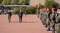 Ein Zivilist und ein Soldat schreiten die Front ab.