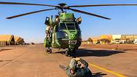 Ein ziviler Fotograf liegt für eine Bildrecherche vor einem Helikopter auf dem Boden