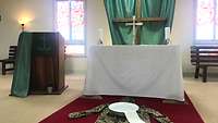 Eine Uniformjacke und eine Schüssel mit Wasser stehen vor dem Altar