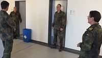 Vier Soldaten die mit großem Abstand auf einem Flur stehen