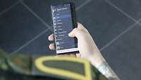 Ein Soldat hält ein Smart-Phone in der Hand.