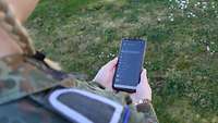 Eine Soldatin hält ein Smartphone in der Hand
