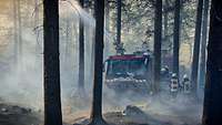 Ein Feuerwehrfahrzeug in einem qualmenden Waldgelände