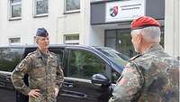 Zwei Soldaten stehen vor einem Gebäude und sprechen über Amtshilfe.