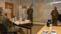 Drei Soldaten in einem Raum bei einer Besprechung an mehreren Lagekarten.