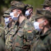 Soldaten stehen mit Mundschutz in einer Gruppe zusammen.