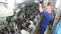 Ein Soldat arbeitet an einem Schiffsdieselmotor