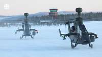 Zwei Kampfhubschrauber Tiger stehen auf einem verschneiten Landeplatz.