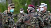 Drei Soldaten stehen im Halbkreis und sprechen miteinander.