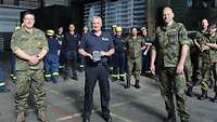 Soldaten und Angehörige vom THW stehen in einem Hangar