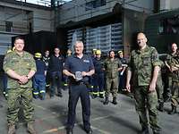 Soldaten und Angehörige vom THW stehen in einem Hangar