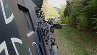 Mehrere Militärfahrzeuge fahren in Kolonne auf einer Straße