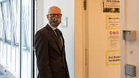 Ein Mann mit Maske vor einer Tür