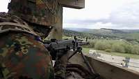 Ein Soldat mit Maschinengewehr im Anschlag (von hinten gesehen) in einem Beobachtungsturm