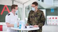Zwei Soldaten mit Mundschutz an einem Stehtisch