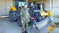 Ein Soldat steht vor einem Radlader. 