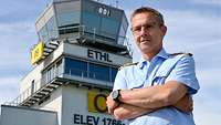 Soldat steht mit verschränkten Armen vor einem Tower. 