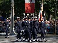 Ecole navale 14. Juli Eine Gruppe von Marinesoldaten in dunklerblauer Uniform, einer trägt eine Fahne mit den Farben Blau-weiß-rot