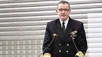 Ein Admiral in dunkelblauer Uniform spricht an einem Pult.