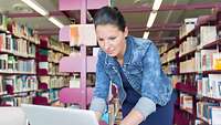 Eine Frau beugt sich über ein Laptop.