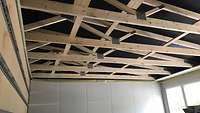 Unverkleidetes Deckengerüst mit Holzbalken und Winkeln