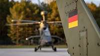Im Vordergrund ein Leitwerk eines Hubschraubers, darauf eine Deutschlandflagge, dahinter unscharf ein weiterer Hubschrauber.