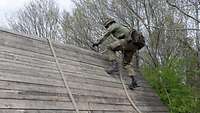 Ein Soldat läuft eine sehr schräge Holzwand nach oben.