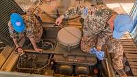 Eine Soldatin und ein Soldat überprüfen den Öl- und Wasserstand am Motor des Transportpanzers Fuchs