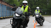 Zwei Soldaten fahren auf zwei Motorrädern um orangefarbene Verkehrshütchen herum.