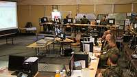Soldaten sitzen in einem großen Zelt vor Computern.
