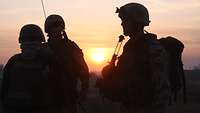 Silhouetten von drei Soldaten bei Sonnenaufgang