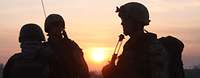 Silhouetten von drei Soldaten bei Sonnenaufgang