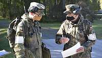 Zwei Soldaten mit Schutzmasken sprechen miteinander.